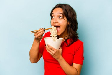 Mavi arka planda izole edilmiş erişte yiyen genç İspanyol kadın.