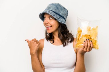 Beyaz arka plan noktalarına izole edilmiş bir paket cipsi tutan genç İspanyol kadın başparmak uzakta, gülüyor ve kaygısız..