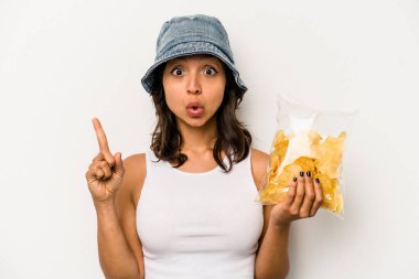 Beyaz arka planda izole edilmiş bir çanta dolusu cipsi tutan genç İspanyol kadının harika bir fikri var, yaratıcılık kavramı..