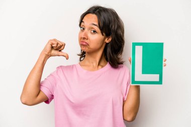 Beyaz arka planda izole edilmiş acemi sürücü tabelasını tutan genç İspanyol kadın gururlu ve kendinden emin hissediyor, örnek olarak..