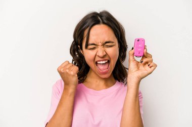 Beyaz arka planda izole edilmiş araba anahtarlarını tutan genç İspanyol kadın zaferden sonra yumruğunu kaldırıyor, kazanan konsept..