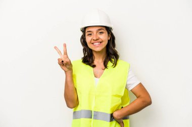 Latin kökenli genç bir kadın beyaz arka planda iki numarayı parmaklarıyla gösteriyor..