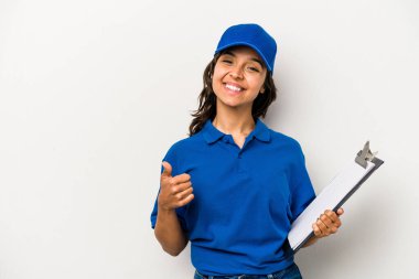Genç İspanyol kadın teslimatçı beyaz arka planda izole edilmiş gülümsüyor ve başparmağını kaldırıyor.