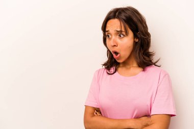 Beyaz arka planda izole edilmiş genç İspanyol kadın gördüğü bir şey yüzünden şoka uğruyor..