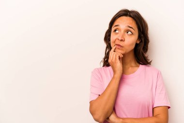 Beyaz arka planda izole edilmiş genç İspanyol kadın şüpheli ve şüpheci bir ifadeyle yana bakıyor..