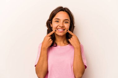 Beyaz arka planda izole edilmiş genç İspanyol kadın gülümsüyor, parmaklarını ağıza doğrultuyor..