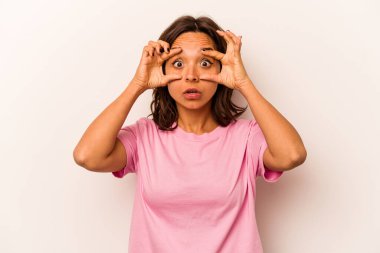 Beyaz arka planda izole edilmiş genç İspanyol kadın bir başarı fırsatı bulmak için gözlerini açık tutuyor..