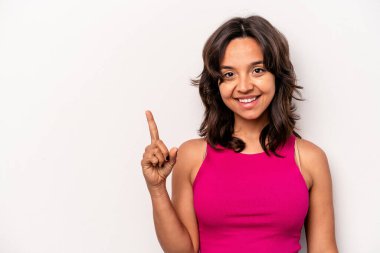 Beyaz arka planda izole edilmiş genç İspanyol kadın bir numarayı parmağıyla gösteriyor..