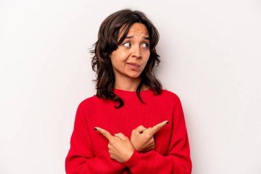 Beyaz arka planda izole edilmiş genç İspanyol kadın iki seçenek arasında seçim yapmaya çalışıyor..