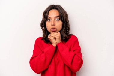 Latin kökenli genç bir kadın beyaz arka planda izole edilmiş şans için dua ediyor, şaşırmış ve ağzı açık bir şekilde önüne bakıyor..