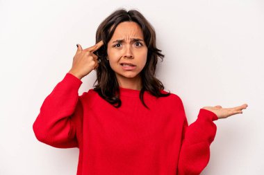 Beyaz arka planda izole edilmiş genç İspanyol kadın elinde bir ürün tutuyor ve.