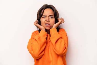 Beyaz arka planda izole edilmiş, kulaklarını parmaklarıyla kapatan, stresli ve çaresiz genç İspanyol kadın yüksek sesli bir ortam tarafından..