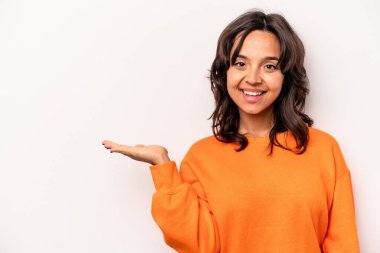 Beyaz arka planda izole edilmiş genç İspanyol kadın bir avuç içinde fotokopi alanı ve belinde bir el daha gösteriyor..