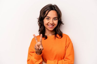 Beyaz arka planda izole edilmiş genç İspanyol kadın zafer işareti gösteriyor ve gülümsüyor..