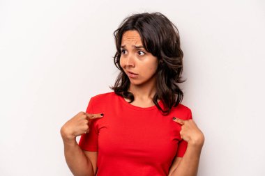 Beyaz arka planda izole edilmiş genç İspanyol kadın parmağını göstererek şaşırdı, geniş bir gülümsemeyle..