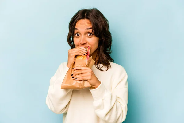 Young Hispanic Woman Eating Sandwich Isolates Blue Background — Stockfoto