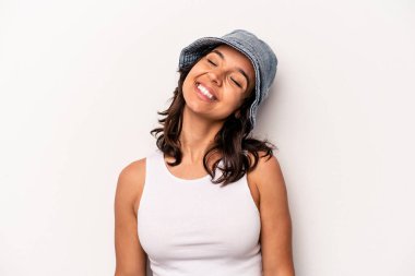 Beyaz arka planda izole edilmiş genç İspanyol kadın gevşemiş ve mutlu bir şekilde gülüyor, boynunda dişlerini gösteriyor..