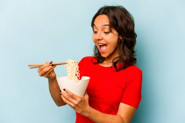 Mavi arka planda izole edilmiş erişte yiyen genç İspanyol kadın.