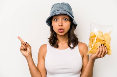 Beyaz arka planda izole edilmiş bir paket cipsi tutan genç İspanyol kadın...