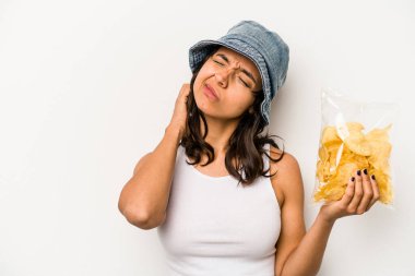 Beyaz arka planda izole edilmiş bir paket cipsi tutan genç İspanyol kadın kafasının arkasına dokunuyor, düşünüyor ve bir seçim yapıyor..