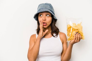 Beyaz arka planda izole edilmiş bir paket cipsi tutan genç İspanyol kadın gizli bir sıcak fren haberi veriyor ve yan bakıyor.