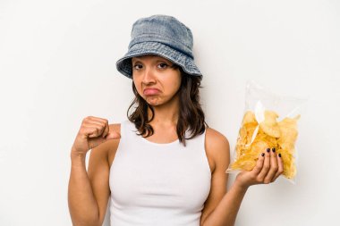 Beyaz arka planda izole edilmiş bir paket cipsi tutan genç İspanyol kadın gururlu ve kendinden emin hissediyor..