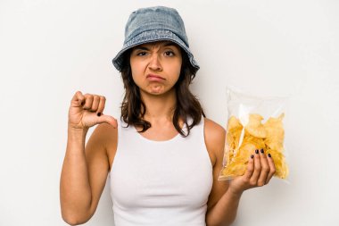 Beyaz arka planda izole edilmiş bir çanta dolusu cipsi tutan genç İspanyol kadın hoşlanmadığı bir hareket gösteriyor. Anlaşmazlık konsepti.