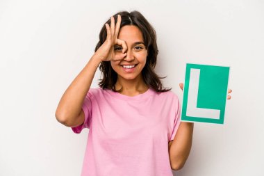 Genç İspanyol kadın elinde acemi sürücü tabelası tutuyor. Beyaz arka planda izole edilmiş. Heyecanlı..