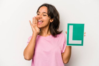 Genç İspanyol kadın elinde acemi sürücü tabelası var beyaz arka planda izole edilmiş bağırıyor ve avuç içini açık tutuyor..