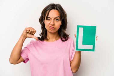 Genç bir İspanyol kadının elinde acemi sürücü tabelası var. Beyaz arka planda izole edilmiş. Sevimsiz bir jest gösteriyor. Anlaşmazlık konsepti.