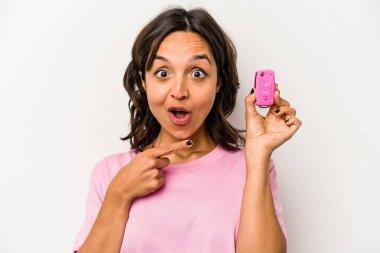 Young hispanic woman holding car keys isolated on white background pointing to the side