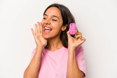 Beyaz arka planda izole edilmiş araba anahtarlarını tutan genç İspanyol kadın bağırıyor ve avuç içini açık tutuyor..