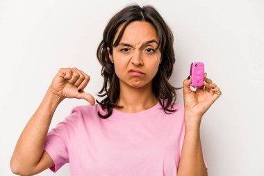 Beyaz arka planda izole edilmiş, hoşlanmadığı bir jest gösteren araba anahtarlarını tutan genç İspanyol kadın. Anlaşmazlık konsepti.