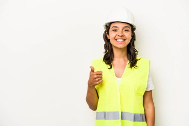 Beyaz arka planda izole edilmiş genç işçi kadın gülümsüyor ve başparmağını kaldırıyor.
