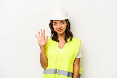 Beyaz arka planda izole edilmiş genç bir işçi kadın gülümseyerek beş numarayı parmaklarıyla gösteriyor..