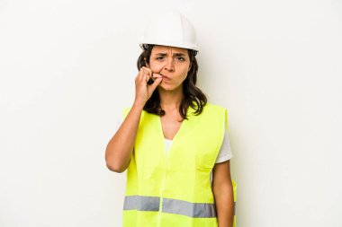 Latin kökenli genç bir kadın beyaz arka planda izole edilmiş, parmakları dudaklarında bir sır saklıyor..