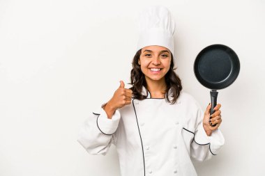 Beyaz arka planda izole edilmiş genç İspanyol aşçı kadın gülümsüyor ve başparmağını kaldırıyor.