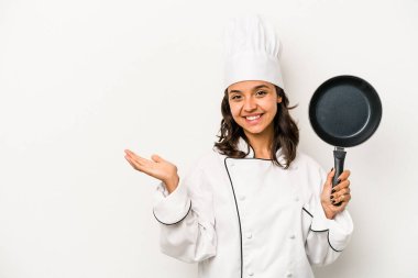 Beyaz arka planda izole edilmiş genç İspanyol aşçı kadın bir avuç içinde fotokopi alanı ve belinde bir el daha gösteriyor..