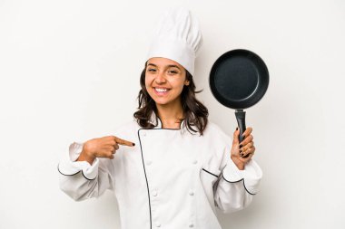 Beyaz arka planda izole edilmiş genç İspanyol aşçı kadın gömlek fotokopisini elle gösteriyor, gururlu ve kendinden emin.