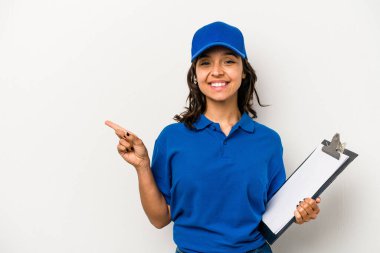 Beyaz arka planda izole edilmiş genç İspanyol kadın teslimatçı. Gülümsüyor ve boş alanda bir şeyler gösteriyor..