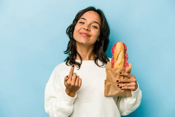 Young Hispanic Woman Eating Sandwich Isolates Blue Background Pointing Finger — Stockfoto