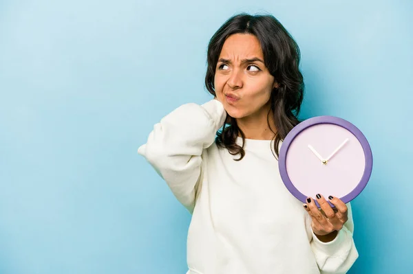Young Hispanic Woman Holding Clock Isolated Blue Background Touching Back — Stok fotoğraf