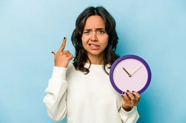 Young Hispanic Woman Holding Clock Isolated Blue Background Showing Disappointment — Fotografie, imagine de stoc