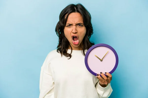 Young Hispanic Woman Holding Clock Isolated Blue Background Screaming Very — Stock fotografie