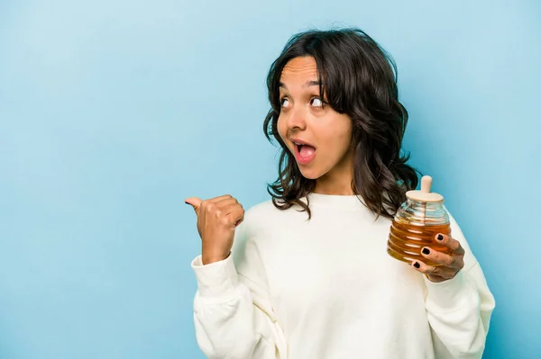 Young Hispanic Woman Holding Honey Isolated Blue Background Points Thumb — Zdjęcie stockowe