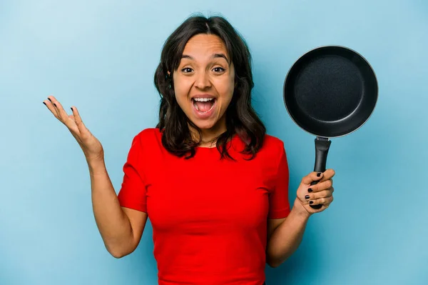 Junge Hispanische Frau Hält Eine Bratpfanne Isoliert Auf Blauem Hintergrund — Stockfoto