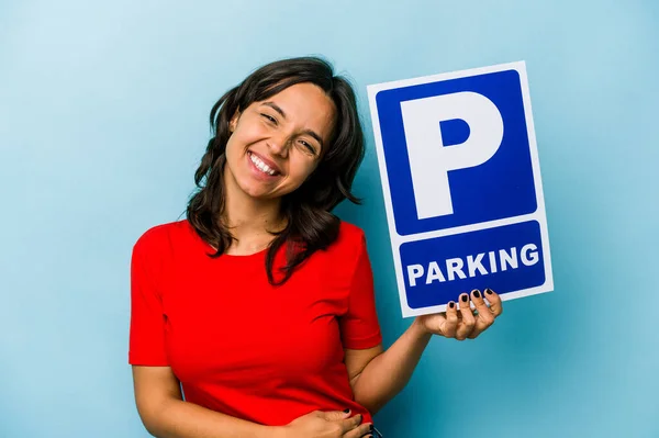Ung Latinamerikansk Kvinna Håller Parkerings Skylt Isolerad Blå Bakgrund Skrattar — Stockfoto