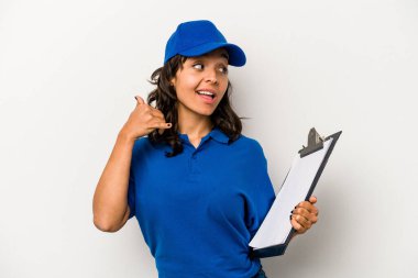 Beyaz arka planda izole edilmiş genç İspanyol kadın teslimatçı parmaklarıyla bir cep telefonu hareketi gösteriyor..