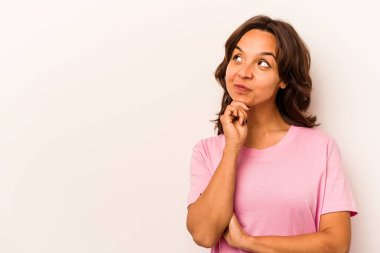 Beyaz arka planda izole edilmiş genç İspanyol kadın şüpheli ve şüpheci bir ifadeyle yana bakıyor..
