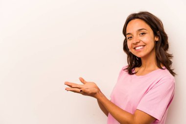 Beyaz arka planda izole edilmiş genç İspanyol kadın avucunun içinde bir kopya alanı tutuyor..